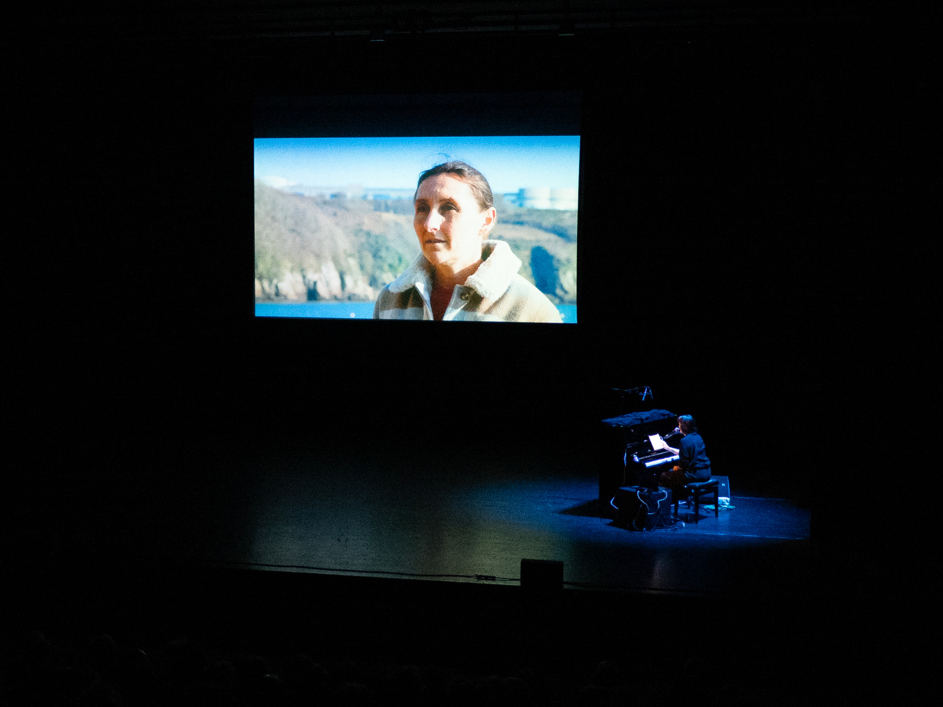 Pianiste sur scène sous un portrait projeté